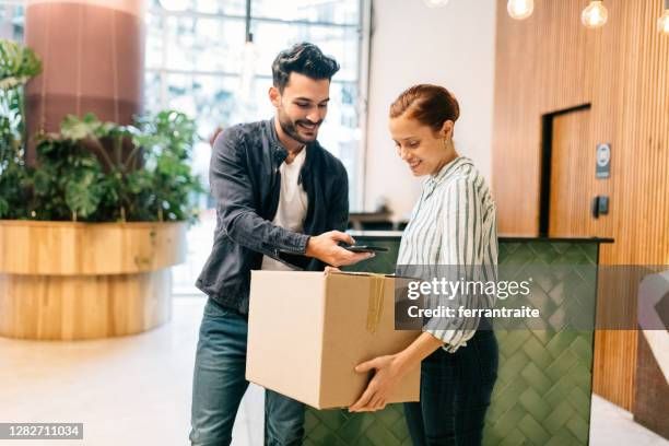 Ein Mann liefert ein Paket an eine Rezeptionistin in einer Hotel-Lobby.
