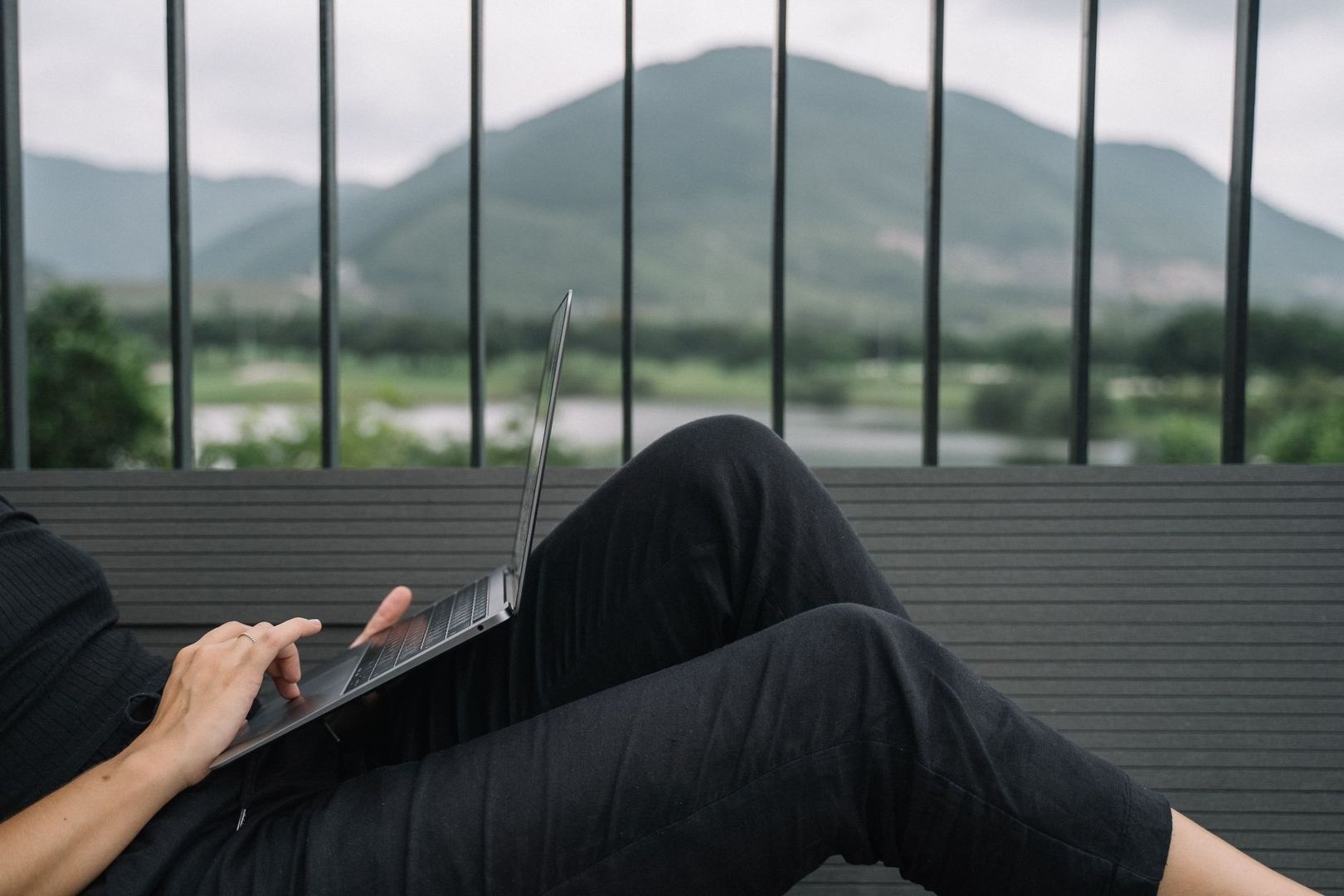 Person arbeitet mit Laptop auf einer Terrasse mit Bergblick