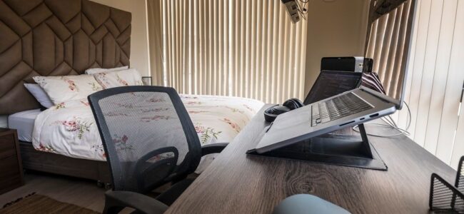 Arbeitsplatz im Schlafzimmer mit Laptopständer, Monitor und Bürostuhl